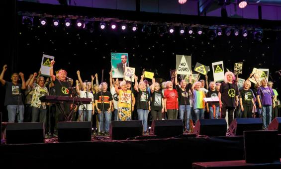 A crowd of people on a stage holding placards.
