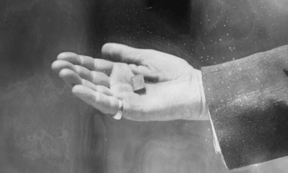 A miniature book sitting in a mans hand