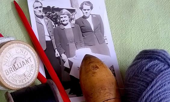 An image of a black and white photo, some yarn and sewing cotton and knitting needles on a green background. 