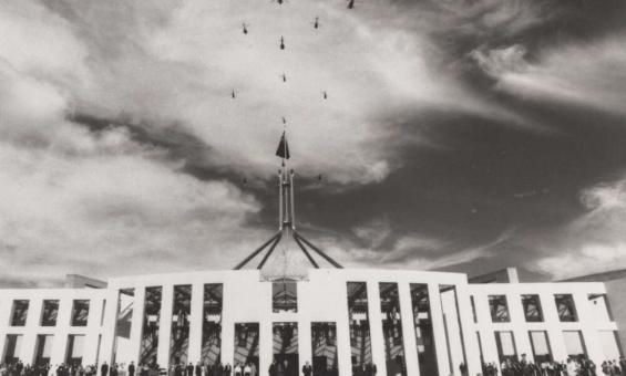 Helicopter flypast above the flagpole of Parliament House, with a crowd gathered below on the steps, Queen visible in the lower right, Canberra, 1988