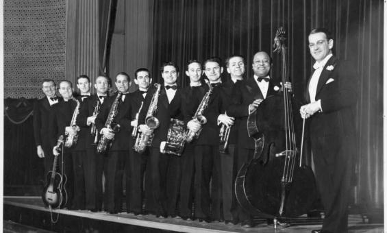 A row of men in concert dress holding musical instruments