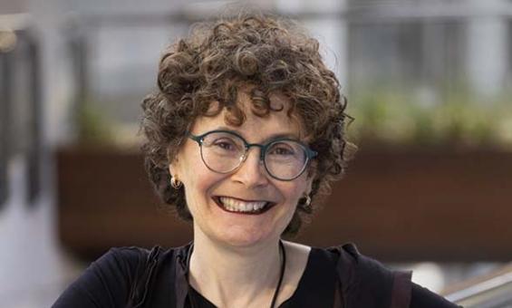 woman leaning against glass partition smiling at camera
