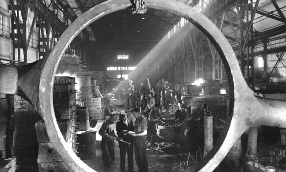 Photograph of employees at BHP steelworks viewed through a cast steel tilting frame of a slag post.