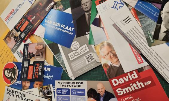 A variety of recently donated 2025 election campaign material laid out on a table. 