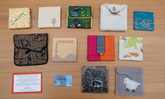 Small handmade diaries of various sizes and designs, some in fabric cases