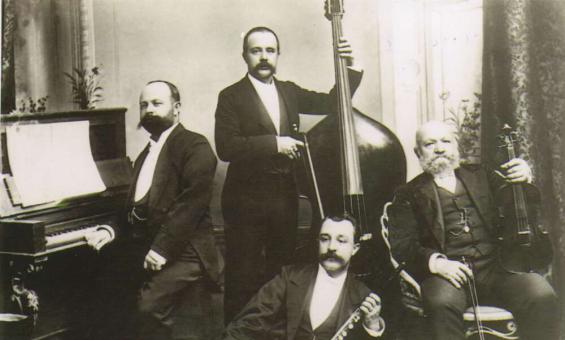 Four men posing in dress suits holding musical instruments.