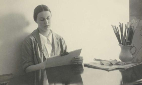 Portrait of Nora Heysen sitting at a desk and painting