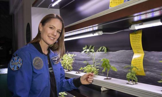 Katherine Bennell-Pegg standing next to plant samples in a lab