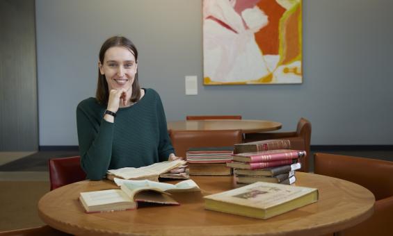Dr Jorien van Beukering sitting at a table with books across it.