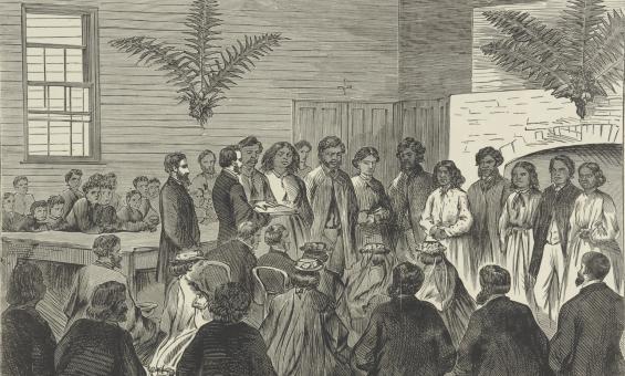 Black and white print of several First Nations people standing in a group, with a man reading from a book in front of them, and several people sitting and watching