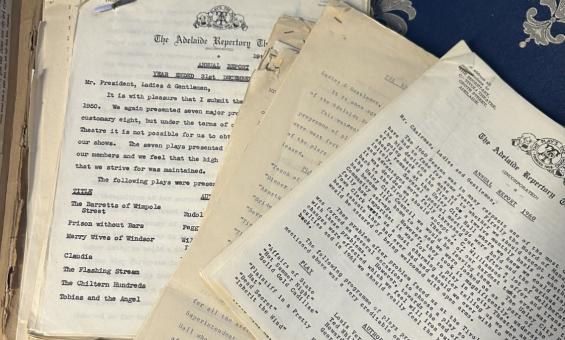 A stack of old papers and reports spread over a desk. 