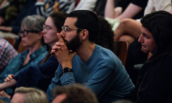 An audience watching a performance in a theatre with a focused expression