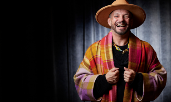 Person in a colourful shawl and large hat laughing