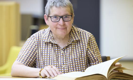 A woman smiling with collection material in the National Library's Special Collections Reading Room