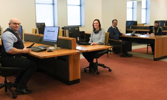 Four members of the Library's Special Collections Research & Support team, two men and two women, sitting at tables in the Main Reading Room